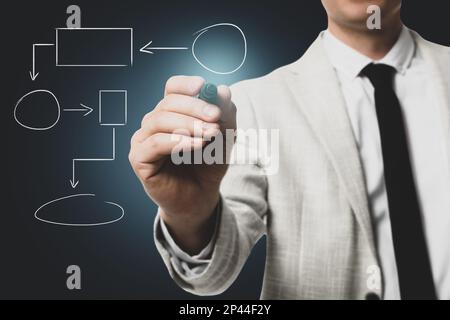 Man pointing at flowchart on virtual screen against dark background, closeup. Business process Stock Photo