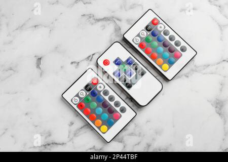 Remote controls on white marble table, flat lay Stock Photo