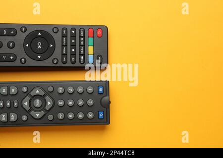 Remote controls on yellow background, flat lay. Space for text Stock Photo