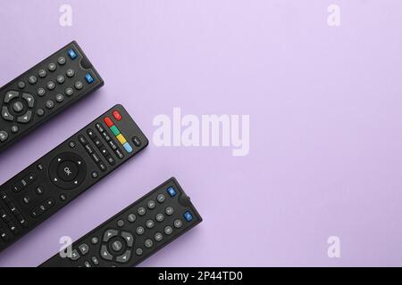 Remote controls on violet background, flat lay. Space for text Stock Photo