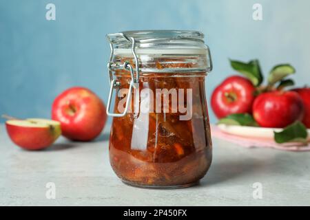Tasty apple jam in glass jar and fresh fruits on light table Stock Photo