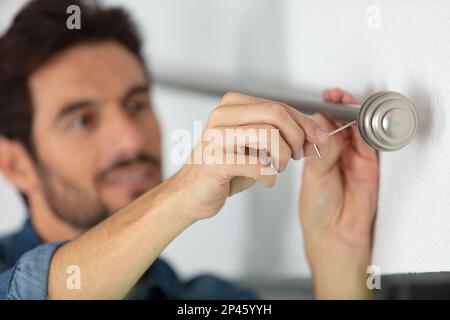 worker installing window curtain rod on the wall Stock Photo