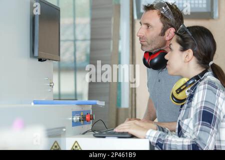 engineer and female apprentice working on machinery in factory Stock Photo