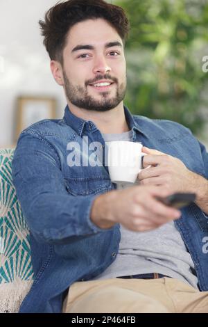 man watching tv while drinking coffee Stock Photo