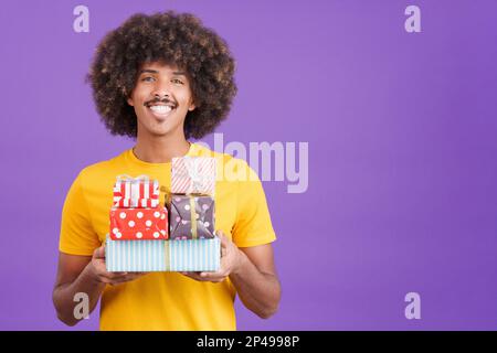 Smiley african man with curly hair holding many gifts Stock Photo