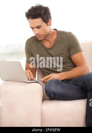 Surfing the net. A handsome young man surfing the net on his laptop at home. Stock Photo