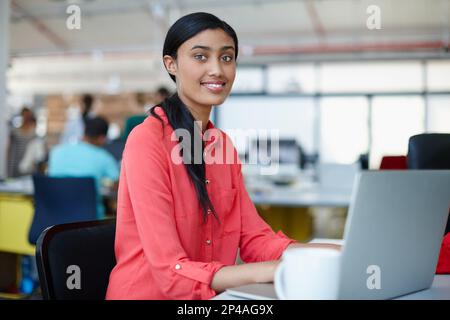 Enjoying her latest project. Portrait of a young female designer working at her computer. Stock Photo