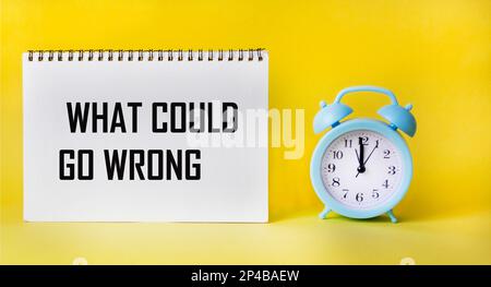 Top view of what can go wrong, text on notepad and yellow background with clock. Business concept. Stock Photo