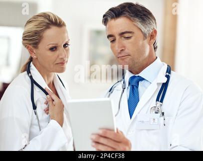 Take a look at this...two doctors talking together over a digital tablet in the hospital. Stock Photo
