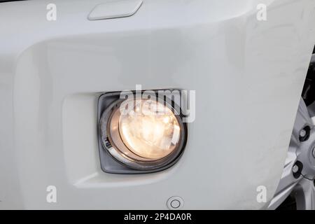Front bumper fog lamp view of silver car after cleaning before sale in a workshop for repair and detailing vehicles auto service industry. Road safety Stock Photo