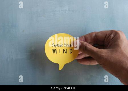 Top view image of hand holding speech bubble with text Speak Your MIND. Motivational quotes concept Stock Photo