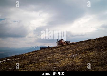 Wooden house on steep mountain slope landscape photo. Nature scenery photography with cloudy background. Ambient light. High quality picture for wallp Stock Photo