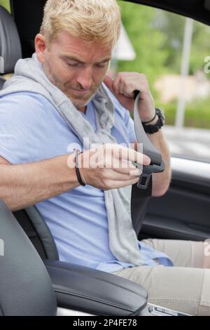 cheerful handsome man adjusting his seatbelt Stock Photo