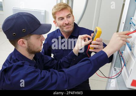 apprentice electrician measuring voltage in distribution board Stock Photo