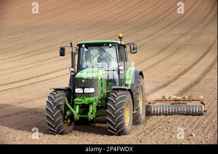 John Deere tractor pulling the soil press, rolling the seedbed in the arable field, Kelso, Scottish Borders, Scotland, United Kingdom Stock Photo