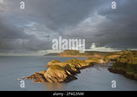 Rain clouds gathering in the evening over the rocky coastal peninsula and bay, Great Hangmans and Combemartin in the distance, Sexton's Burrows Stock Photo