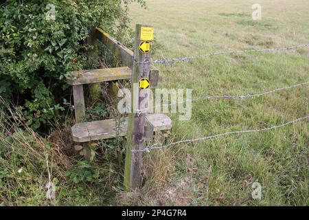 'Public Footpath' and 'Farmland, Please keep your dog on a lead' signs, beside stile at edge of field, Haughley, Suffolk, England, United Kingdom Stock Photo