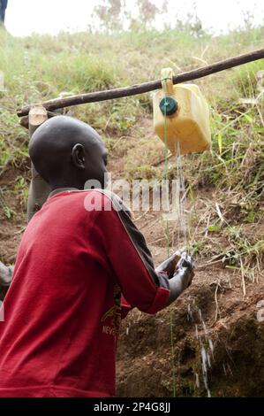 Child washes hands under self-made tap, Rwanda Stock Photo
