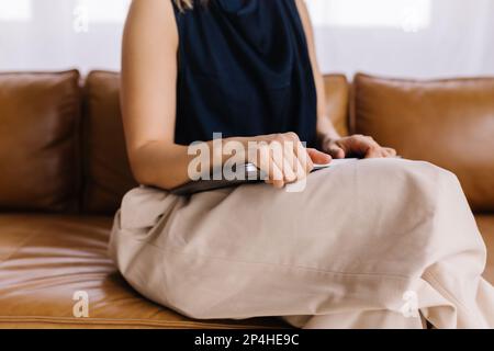 White stylish businesswoman sitting on leather couch holding laptop Stock Photo