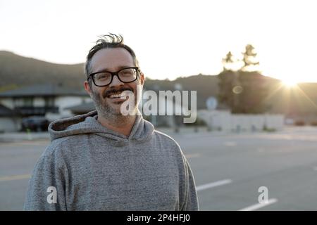 Middle Aged Man With Glasses Smiles While outside At Sunset Stock Photo
