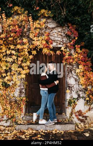 couple in gray jackets and jeans embrace against autumn Prague Stock Photo