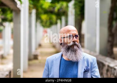 man posing standing with his hands in his pockets in a city park. Stock Photo