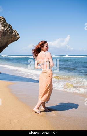 Solo Woman in a bikini with towel at the beach in Puerto Rico Stock Photo