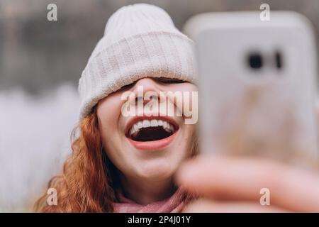 Curly redhead woman 30-35 with a hat over her eyes, she laughs Stock Photo