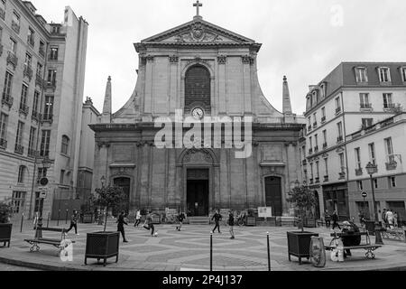 Black and white photo of boys playing football in front of the Basilica of Notre-Dame des Victories, in the 2nd Arrondissement of Paris. Stock Photo