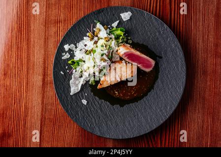 grilled tuna steak with sauce in a plate on a wooden table Stock Photo
