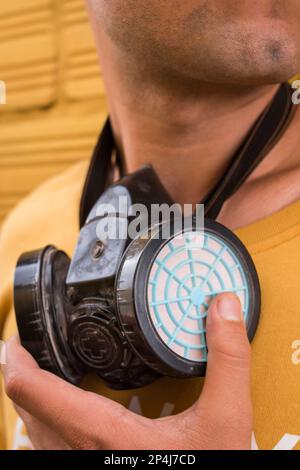 Man holding a gas mask on yellow background Stock Photo
