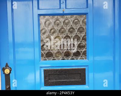 Detail of a decorative window in a bright blue door. Stock Photo