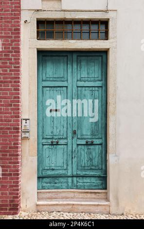 Old scratched turquoise wooden entrance door of a historic building Stock Photo