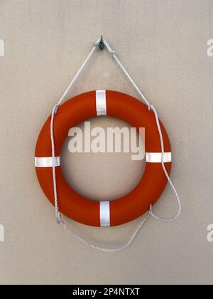 rescue ring mounted or hanging on a textured concrete wall. life saving device. life guard concept. Stock Photo