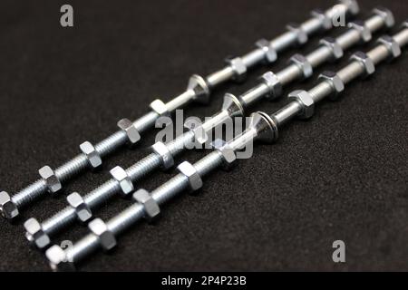 Shiny Iron Bolts With Nuts Screwed On Them Lie In Even Rows Isolated On Black Surface Stock Photo