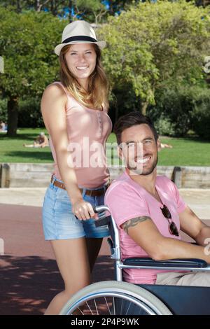 young couple in wheelchair strolling in the park Stock Photo