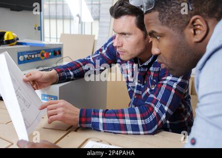 male colleagues study plans in a factory Stock Photo