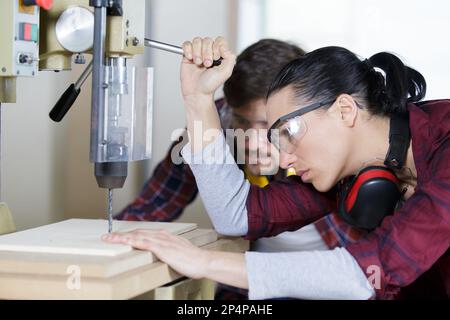 woman using bench drill under supervision Stock Photo
