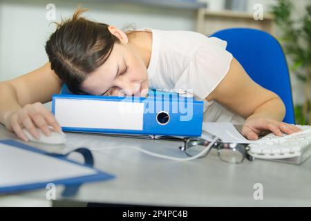 woman fallen asleep while working at office desk Stock Photo