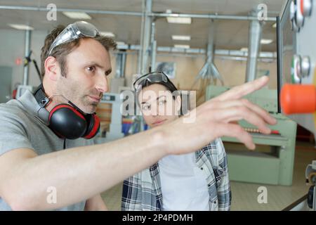 engineer training female apprentice on cnc machine Stock Photo