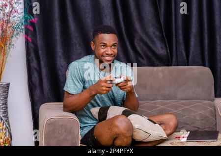 Close up of attractive hipster with bristle and toothy grin, holding joy stick and playing videogames on tv at vacation Stock Photo