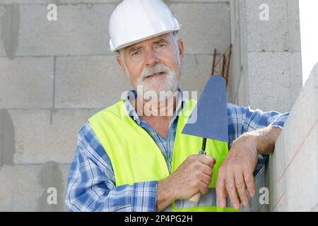 senior mason holding a trowel on site Stock Photo