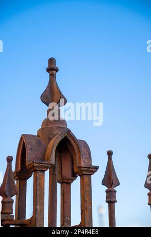 Rusted iron, ornamental gate post with clear blue sky in background. Stock Photo