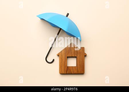 Mini umbrella and house model on beige background, flat lay Stock Photo