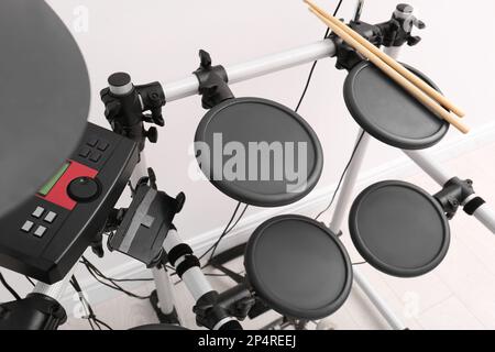 Modern electronic drum kit near white wall indoors. Musical instrument Stock Photo