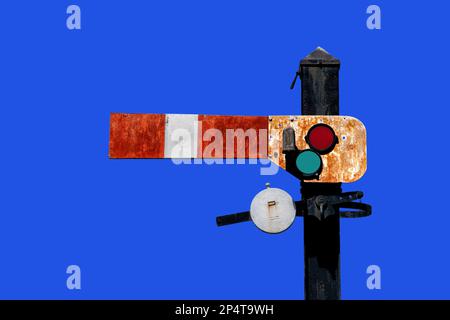 Old vintage italian railway traffic light indicator showing, signal with red orange and green len isolated on blue sky with clipping path included Stock Photo