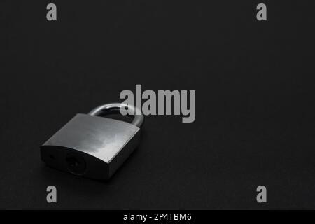 Steel padlock on black surface with copy space Stock Photo