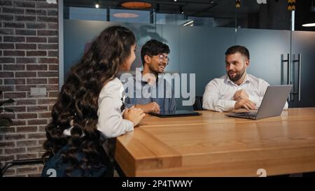 Three diverse business partners multiracial work group team developing new project multinational colleagues smiling working with laptop brainstorming Stock Photo