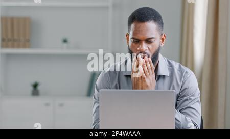 Depressed african businessman frustrated after reading bad news upset man having problem, feels desperate by business failure sitting at office desk Stock Photo