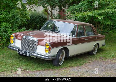 Lamorlaye, France - July 05 2020: Old Mercedes-Benz 280SE parked by a tree. Stock Photo